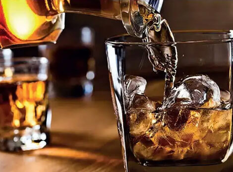 Drink being poured into a glass with ice